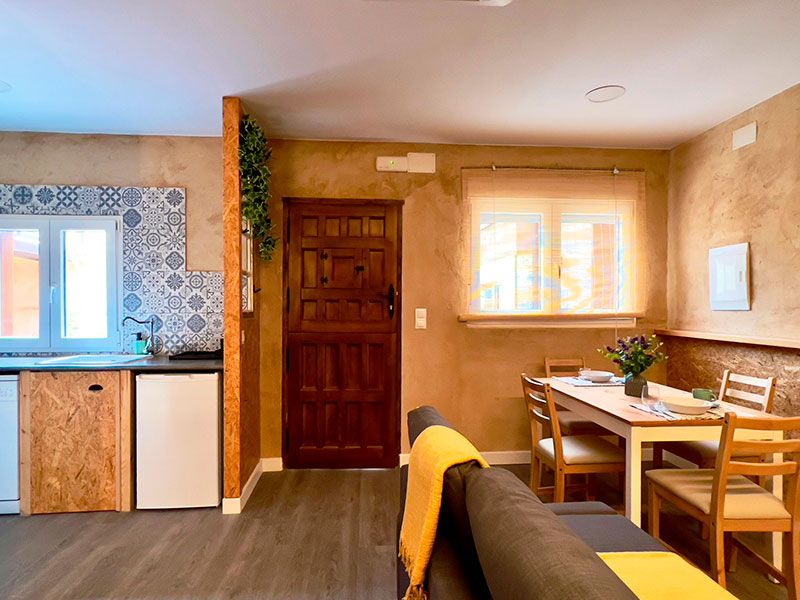 Salón cocina con sofá gris y mesa de comedor