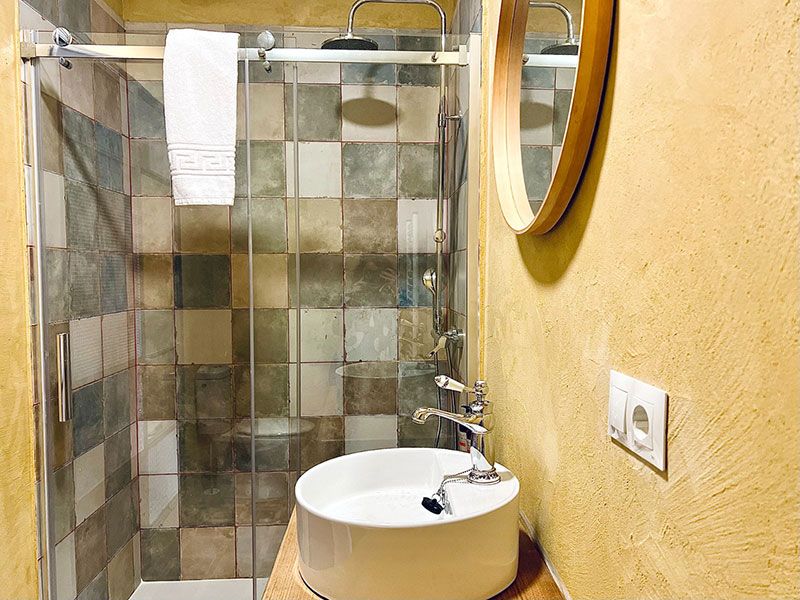 Baño con ducha con mampara, lavamanos con pila redonda exenta y espejo