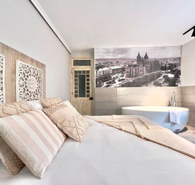 Cama de matrimonio con cabecero artesanal de madera y bañera