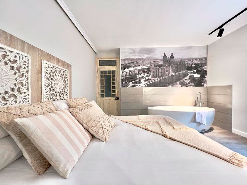 Cama de matrimonio con cabecero artesanal de madera y bañera