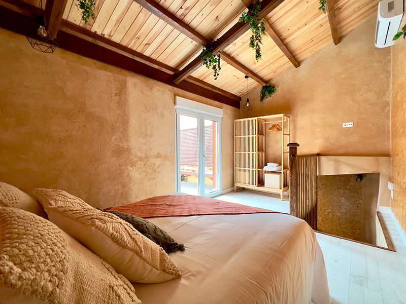 Cama de matrimonio en habitación abuhardillada y estantería