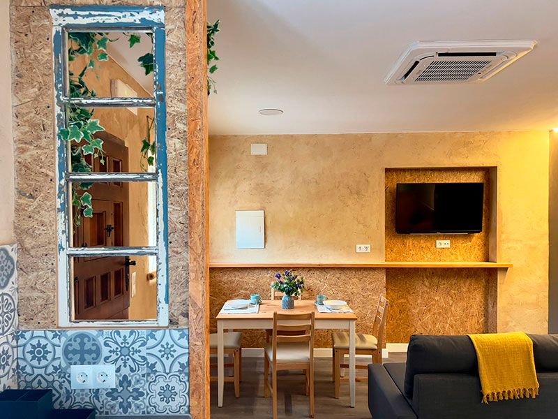 Ventana rústica y salón cocina con sofá y mesa