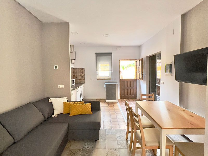 Salón con sofá, mesita y cocina al fondo