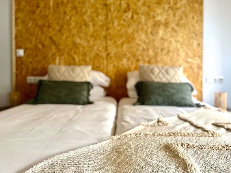 Camas dobles decoradas con almohadas y pared de madera