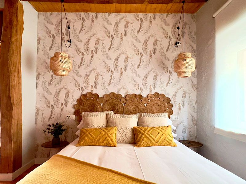Cama de matrimonio con cabecero de mimbre y cojines amarillos